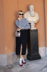 a lady in a grey sweater and a long black slit denim skirt